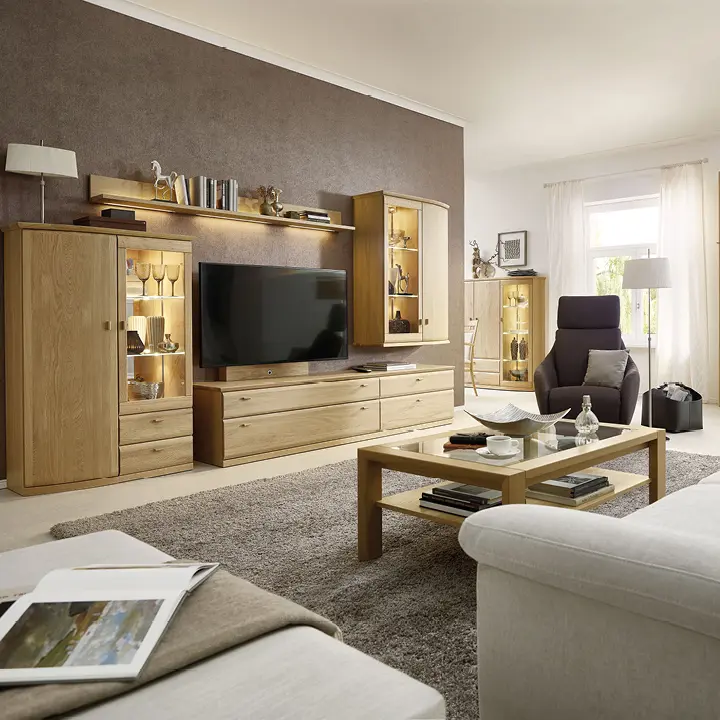 Wohnwand aus Eiche mit TV, Vitrinen, Couchtisch und Sessel im hellen Wohnzimmer